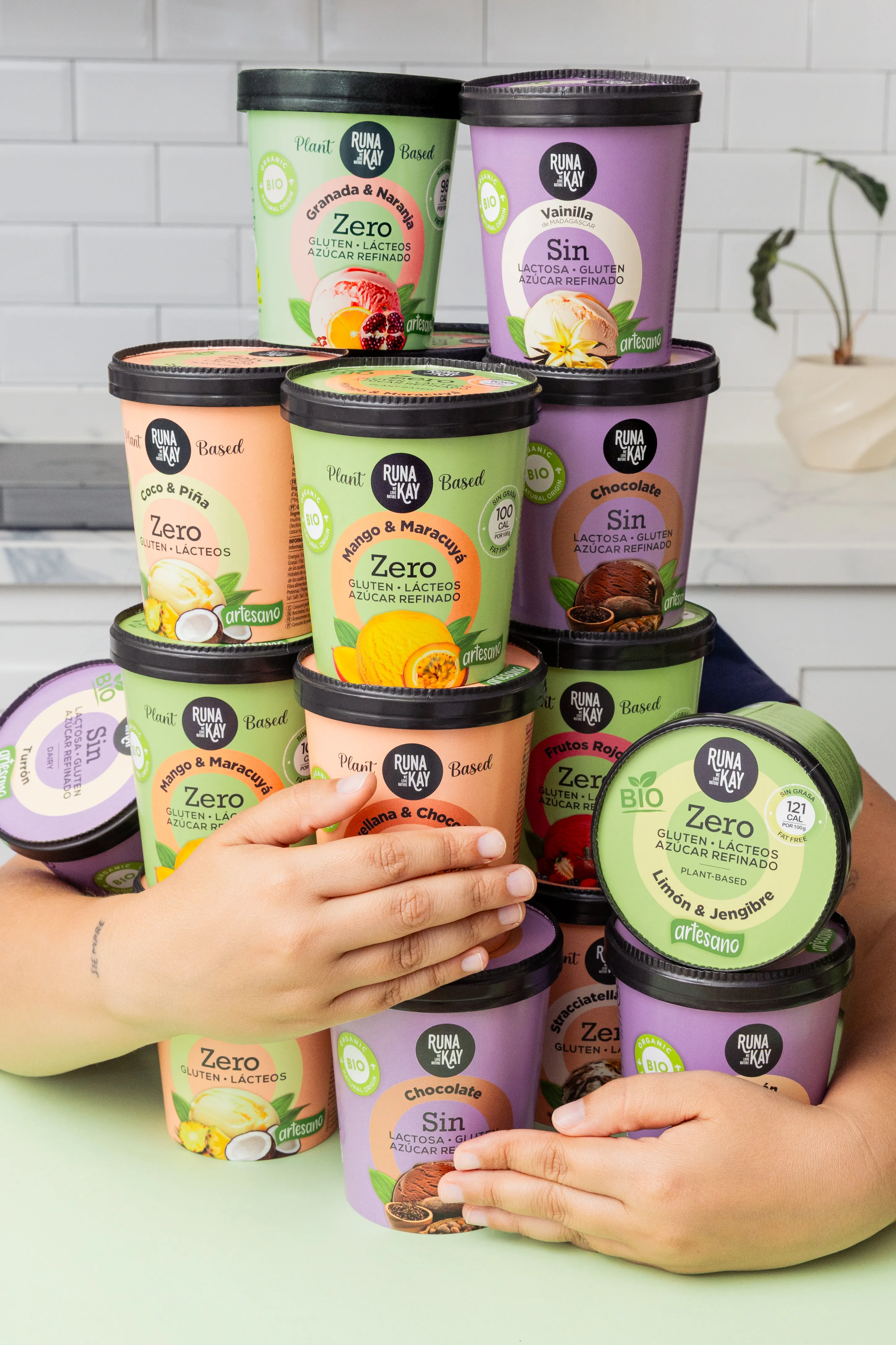 Manos sosteniendo una pila de tarrinas de helado Runakay de distintos sabores